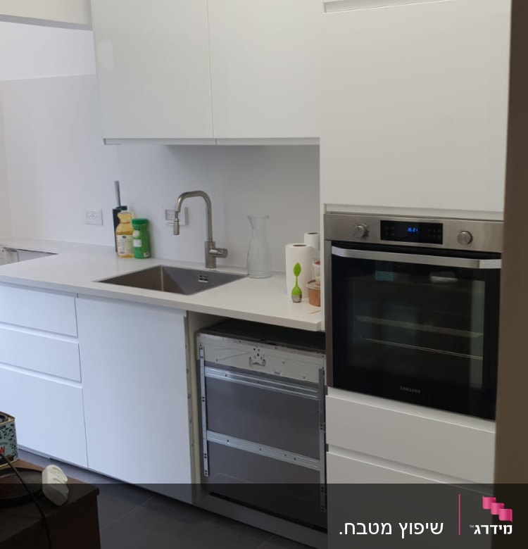 מטבח עם ארונות לבנים, כיור וברז מותקנים